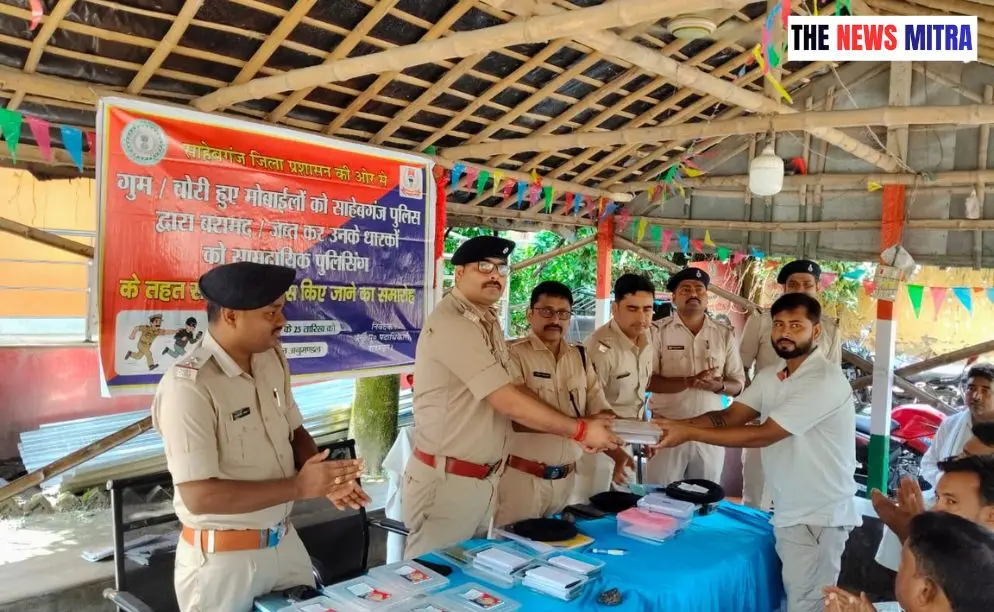 धारक को मोबाइल सौंपते पुलिस पदाधिकारी व मौजूद अन्य
